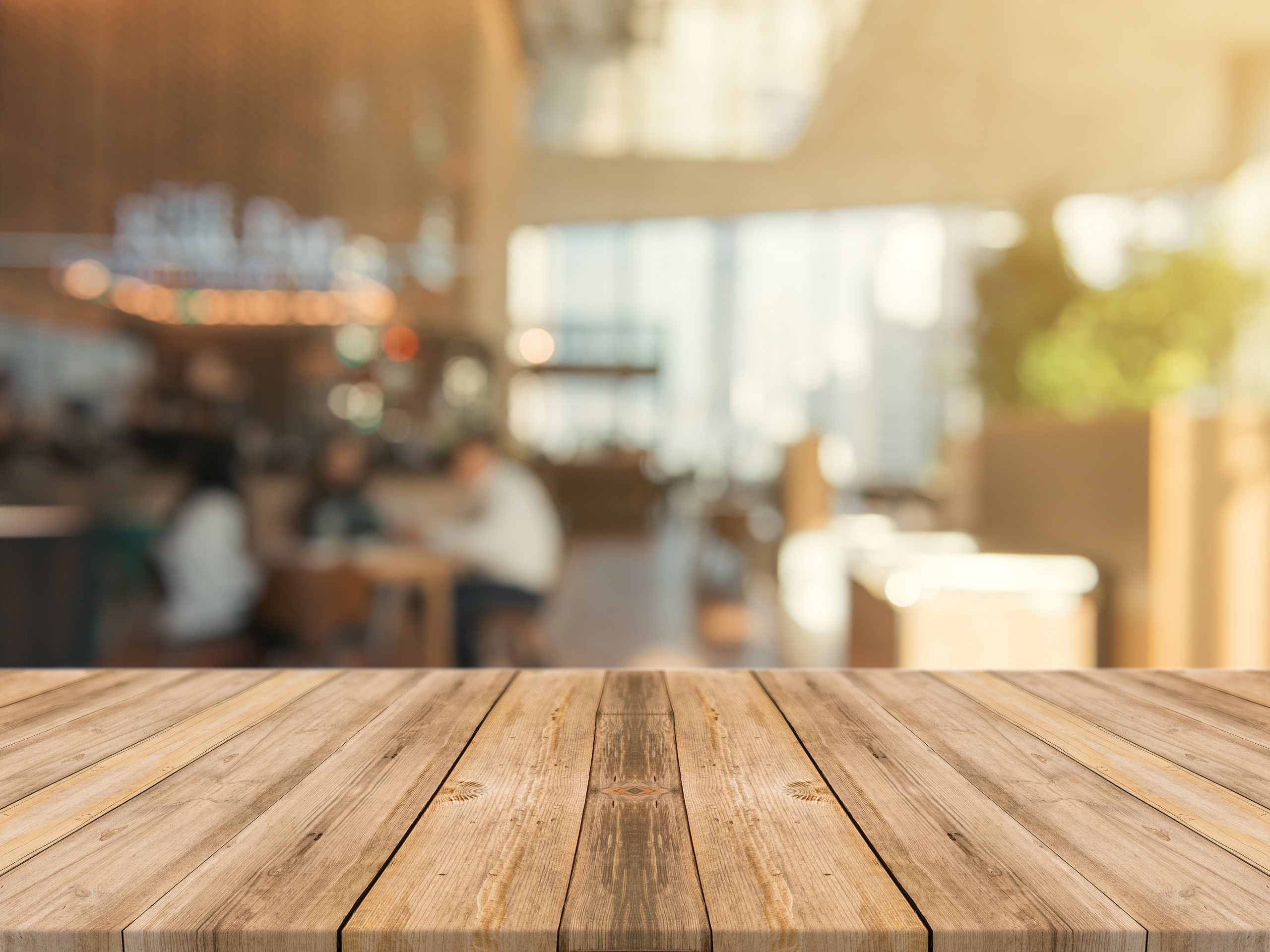 Wooden board empty table top on of blurred background. Perspective brown wood table over blur in coffee shop background - can be used mock up for montage products display or design key visual layout.